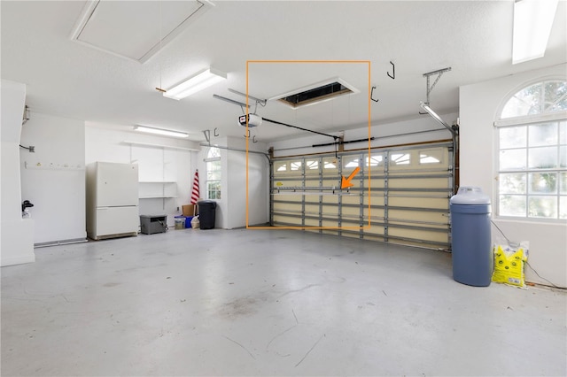 garage featuring a garage door opener and white refrigerator