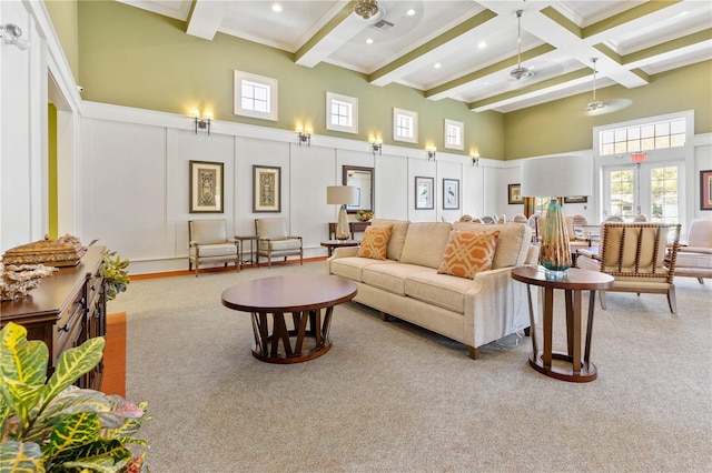 carpeted living room with beamed ceiling, a high ceiling, and french doors