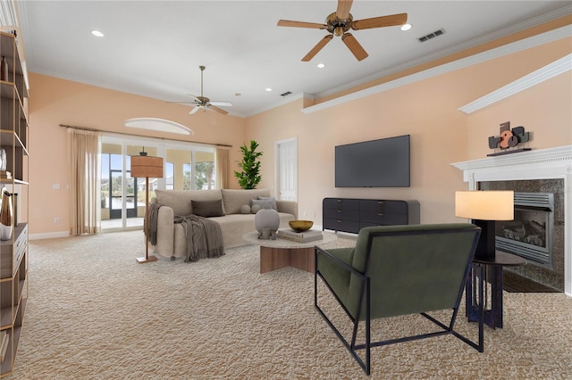 carpeted living room with ceiling fan, a premium fireplace, and crown molding