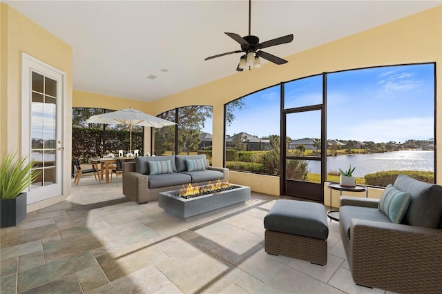 sunroom with ceiling fan and a water view