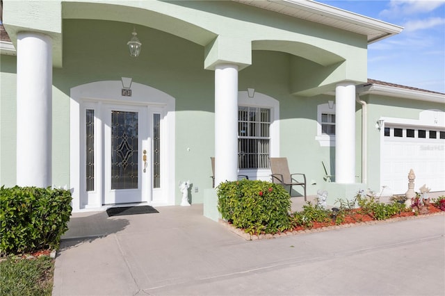 view of exterior entry with a garage and stucco siding