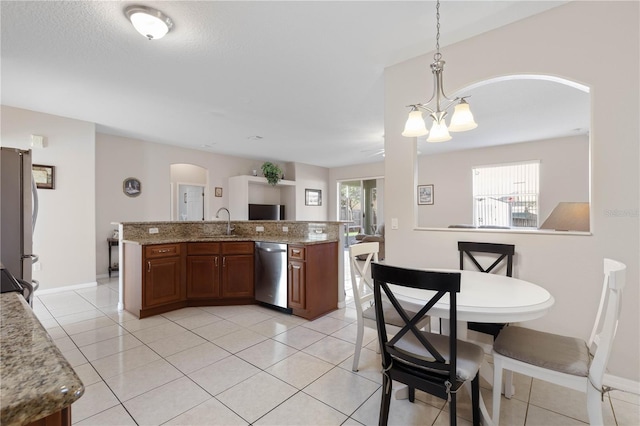 kitchen with appliances with stainless steel finishes, a kitchen island with sink, light tile patterned floors, pendant lighting, and a chandelier