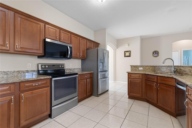 54 Fieldstone Ln, Palm Coast, FL 32137 - kitchen featuring appliances with stainless steel finishes, light tile patterned floors, arched walkways, and brown cabinets