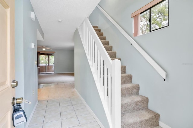 staircase featuring ceiling fan, tile patterned flooring, and a textured ceiling