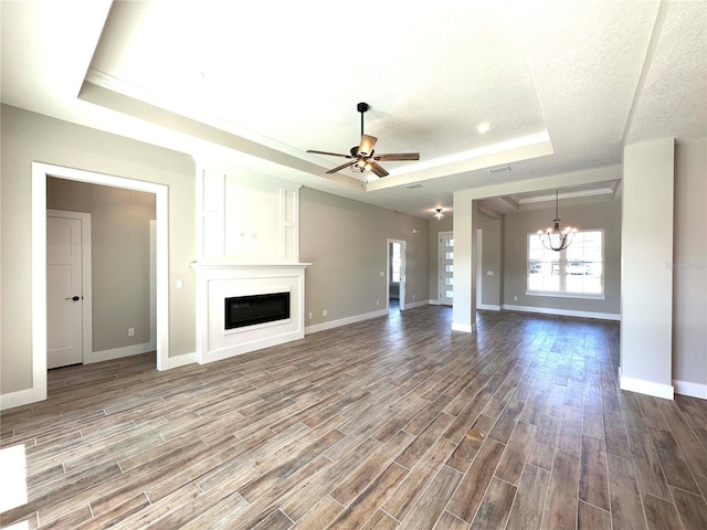 unfurnished living room featuring hardwood / wood-style floors, ceiling fan with notable chandelier, a textured ceiling, and a raised ceiling