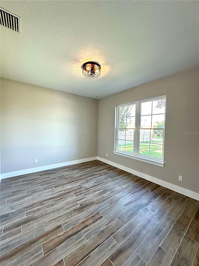 spare room with wood-type flooring and a textured ceiling