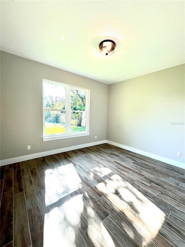 spare room featuring dark hardwood / wood-style flooring and a textured ceiling