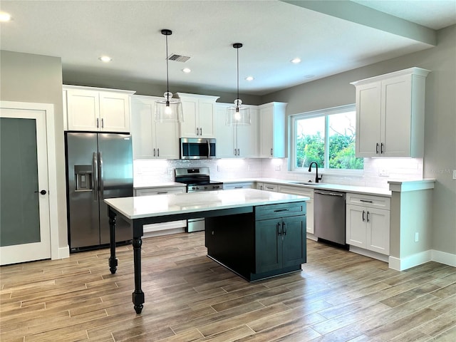 36 Armand Beach Dr, Palm Coast, FL 32137 - kitchen with appliances with stainless steel finishes, a kitchen island, light wood finished floors, light countertops, and white cabinetry