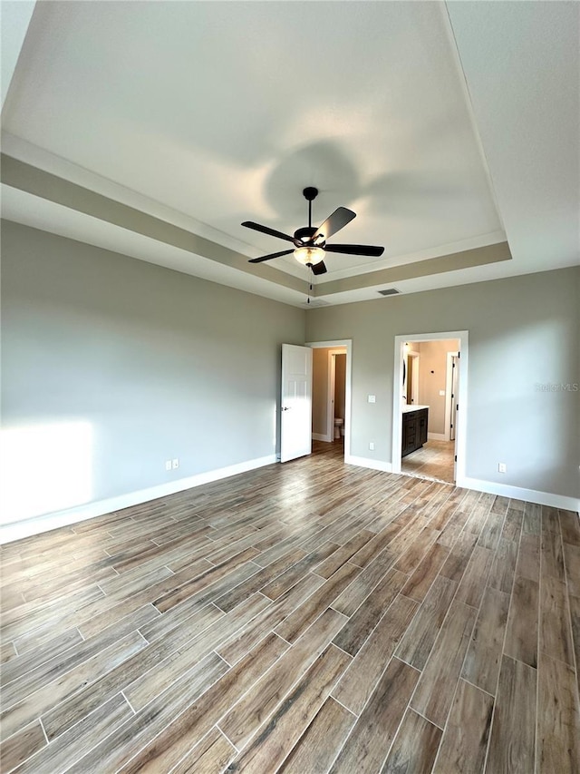 36 Armand Beach Dr, Palm Coast, FL 32137 - unfurnished bedroom with a tray ceiling, wood finished floors, connected bathroom, and a ceiling fan