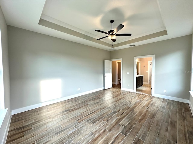 36 Armand Beach Dr, Palm Coast, FL 32137 - unfurnished bedroom with a tray ceiling, wood finished floors, ensuite bathroom, and a ceiling fan