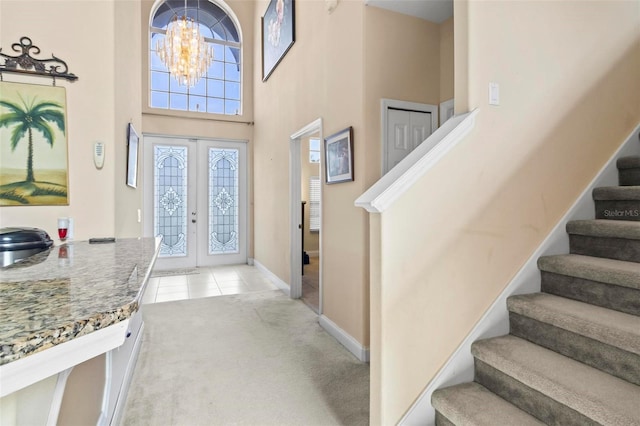 carpeted foyer with a high ceiling, an inviting chandelier, and french doors