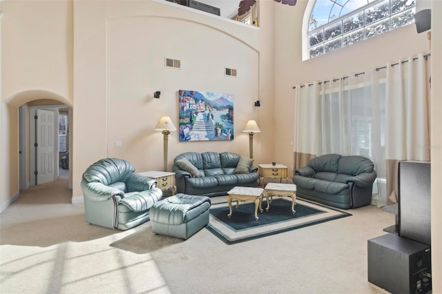 carpeted living room featuring a towering ceiling