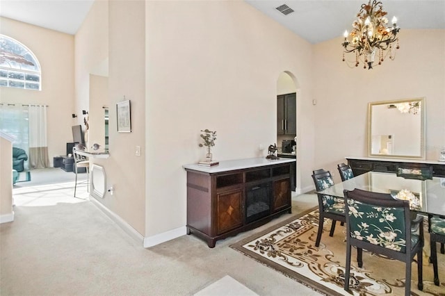 interior space with a towering ceiling, a notable chandelier, dark brown cabinets, and light colored carpet