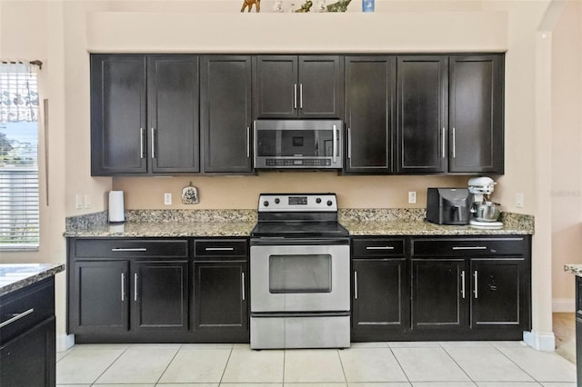 kitchen with stainless steel appliances, light tile patterned flooring, and light stone counters