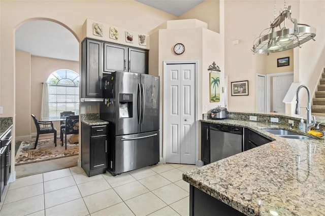 kitchen featuring stainless steel appliances, sink, light stone counters, a towering ceiling, and light tile patterned floors