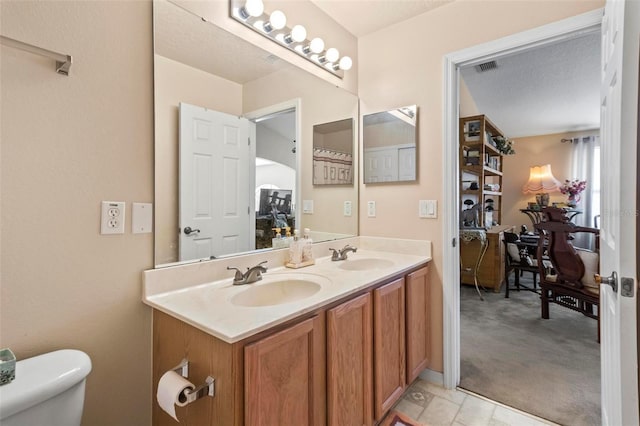 bathroom with a textured ceiling, vanity, and toilet