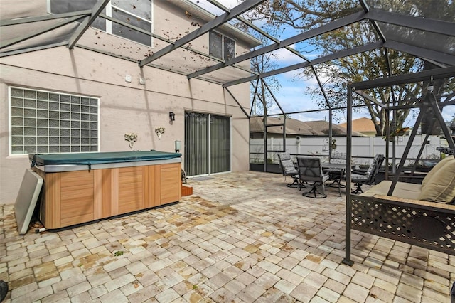 view of patio with glass enclosure and a hot tub