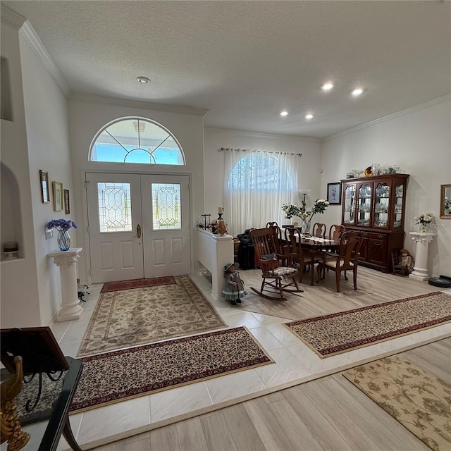 foyer featuring crown molding, light tile patterned floors, and a textured ceiling