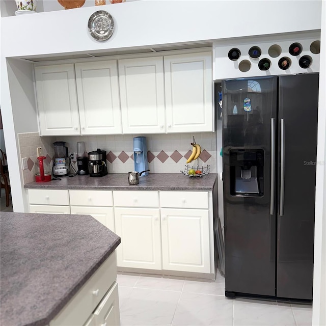 kitchen featuring light tile patterned floors, backsplash, white cabinetry, and black refrigerator with ice dispenser