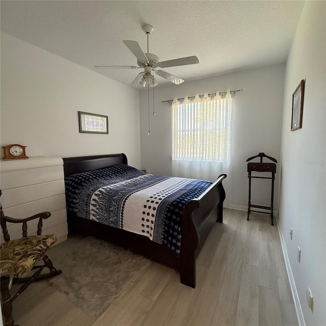 bedroom featuring ceiling fan, a textured ceiling, and light hardwood / wood-style flooring