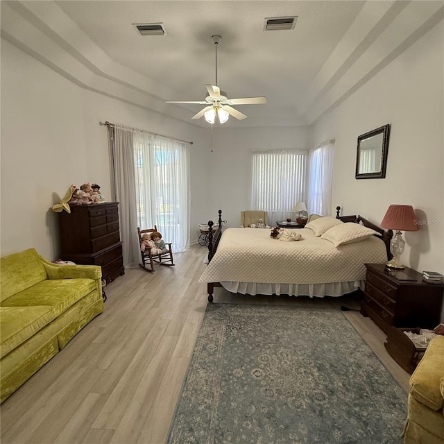 bedroom featuring a tray ceiling, ceiling fan, and light hardwood / wood-style floors