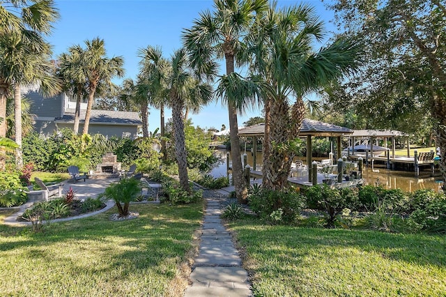 view of home's community featuring a boat dock, a water view, and a yard