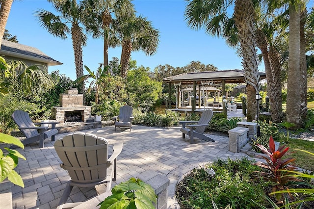 view of patio with a gazebo and an outdoor stone fireplace