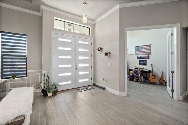 entrance foyer featuring crown molding, a textured ceiling, and light wood-type flooring