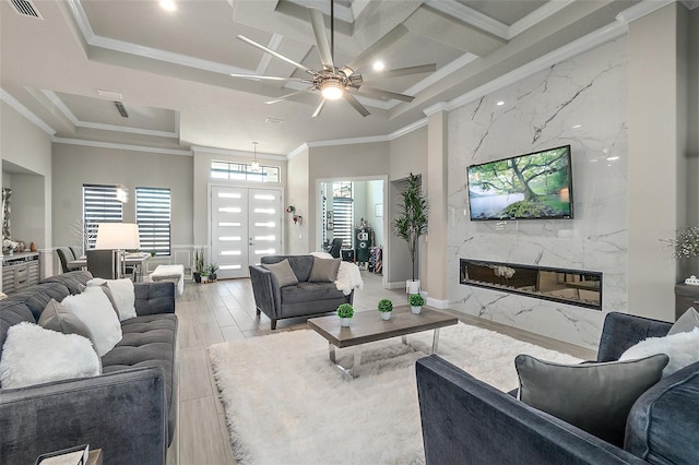 living room featuring light wood-type flooring, a wealth of natural light, crown molding, and a premium fireplace