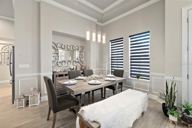 dining room featuring hardwood / wood-style flooring, a towering ceiling, and crown molding