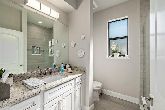 bathroom with hardwood / wood-style floors, vanity, toilet, and a shower with door