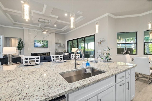 kitchen with coffered ceiling, white cabinetry, a healthy amount of sunlight, and sink