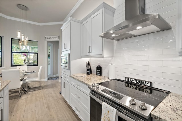 kitchen with white cabinetry, wall chimney exhaust hood, tasteful backsplash, appliances with stainless steel finishes, and light wood-type flooring