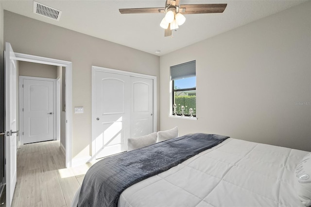 bedroom with ceiling fan, light wood-type flooring, and a closet