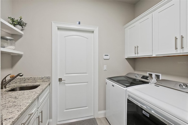 clothes washing area featuring cabinets, washing machine and dryer, sink, and hardwood / wood-style flooring