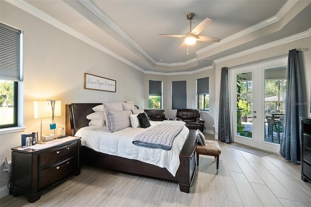 bedroom featuring access to exterior, french doors, ornamental molding, a tray ceiling, and ceiling fan