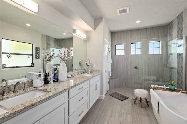 bathroom with hardwood / wood-style flooring, vanity, separate shower and tub, and a textured ceiling