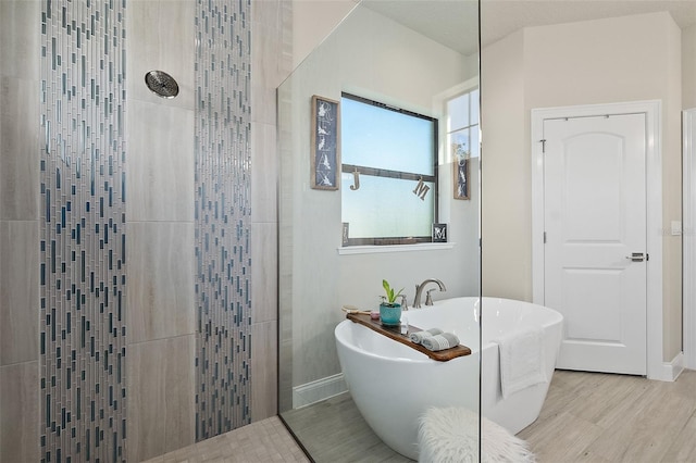 bathroom with wood-type flooring and shower with separate bathtub