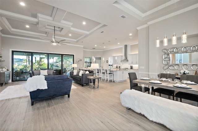 living room featuring ceiling fan, ornamental molding, coffered ceiling, and light wood-type flooring