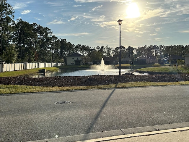 view of street featuring curbs, a water view, and street lights