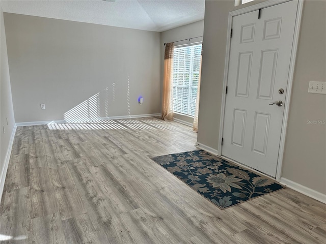 entrance foyer featuring a textured ceiling, baseboards, and wood finished floors