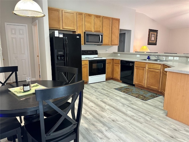 kitchen featuring lofted ceiling, a sink, black appliances, light countertops, and light wood-type flooring