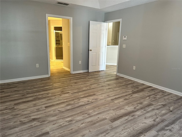 spare room featuring visible vents, baseboards, and wood finished floors