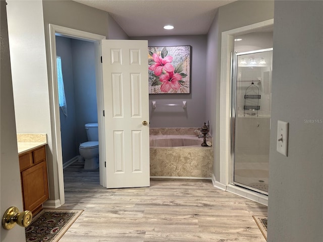 full bathroom featuring a bath, a stall shower, toilet, and wood finished floors