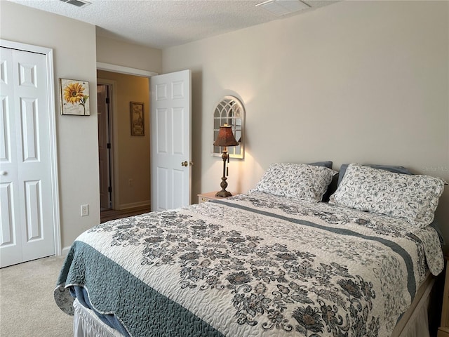 bedroom with carpet, visible vents, a closet, and a textured ceiling