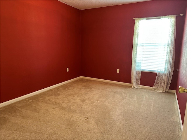 carpeted empty room featuring baseboards