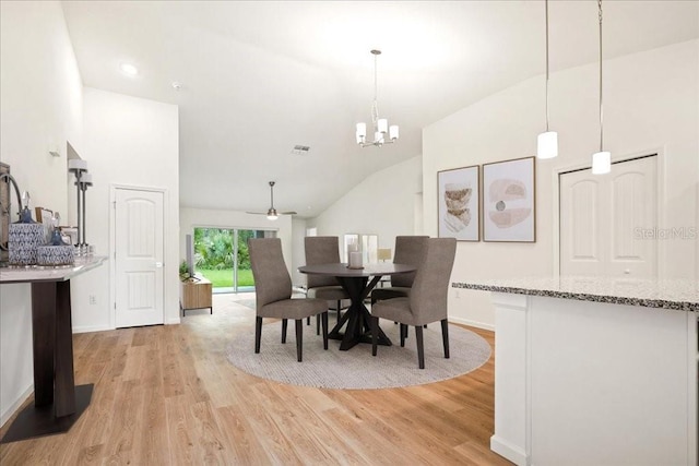 dining space featuring ceiling fan with notable chandelier, vaulted ceiling, and light wood-type flooring