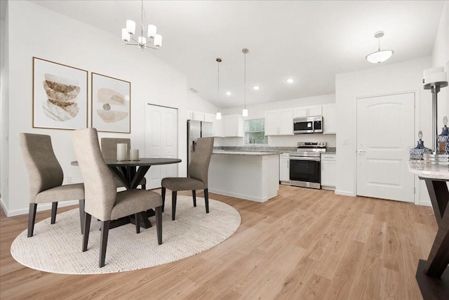 dining space with a notable chandelier, lofted ceiling, and light hardwood / wood-style flooring