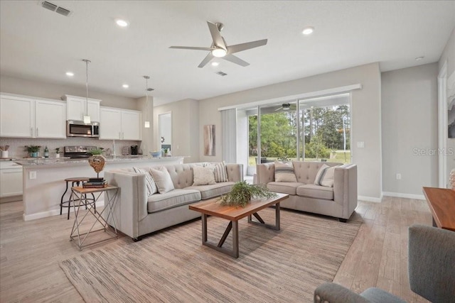 living room with ceiling fan and light hardwood / wood-style flooring