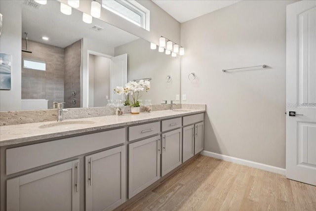 bathroom with plenty of natural light, a tile shower, wood-type flooring, and vanity